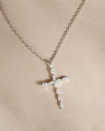 Sterling silver dainty cross necklace on a beige background