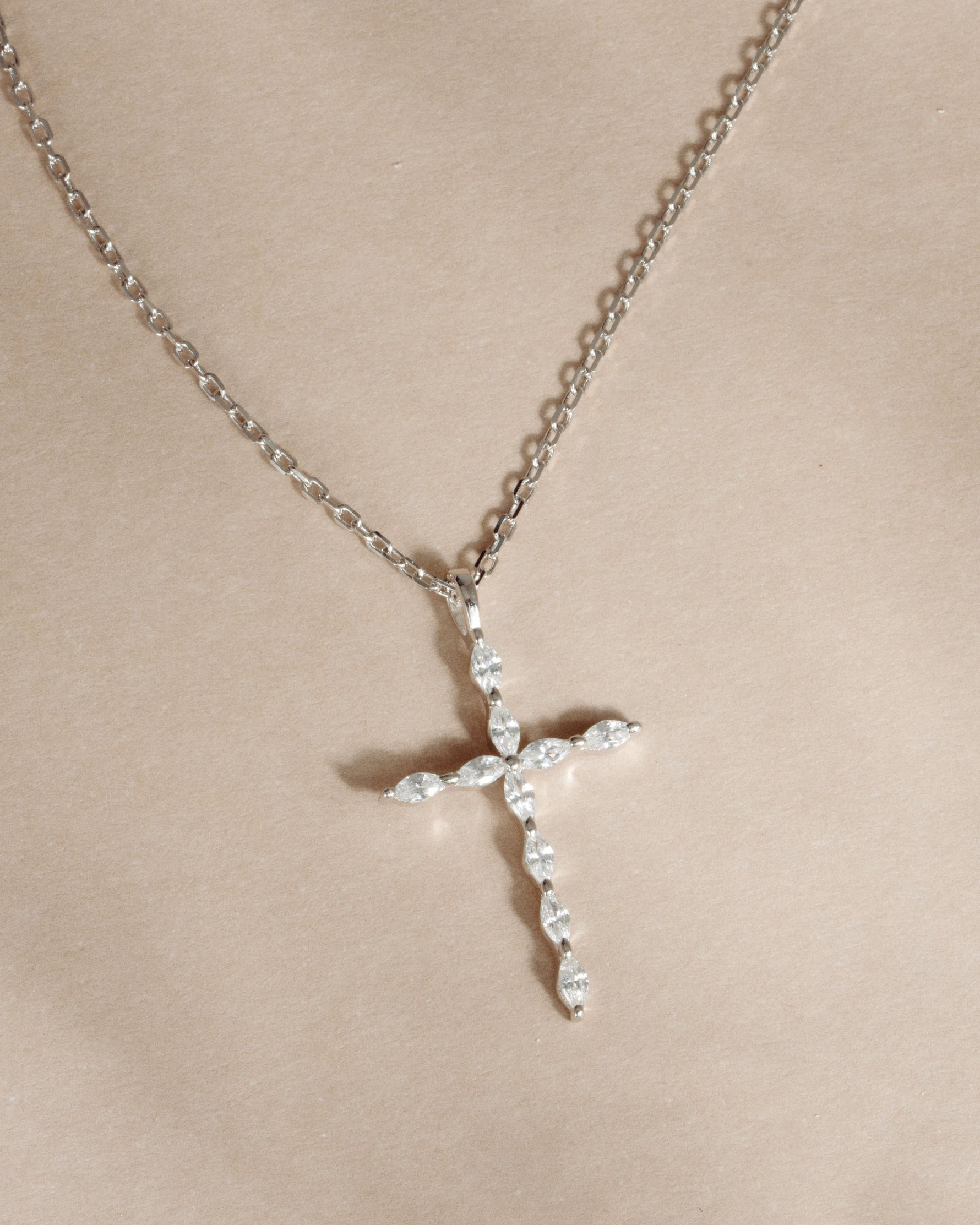 Sterling silver dainty cross necklace on a beige background