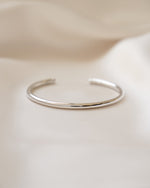 925 sterling silver cuff bracelet on a soft beige fabric background