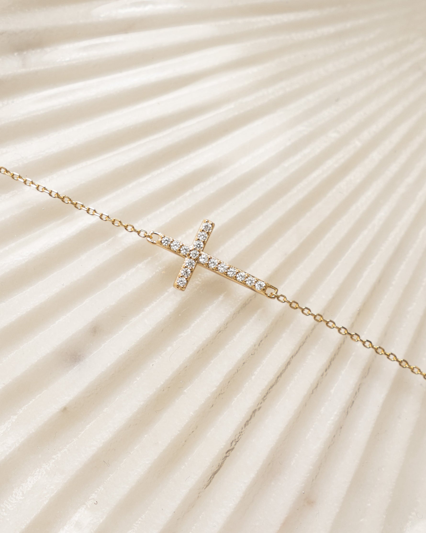 Gold cross bracelet religious jewelry on a  textured beige background