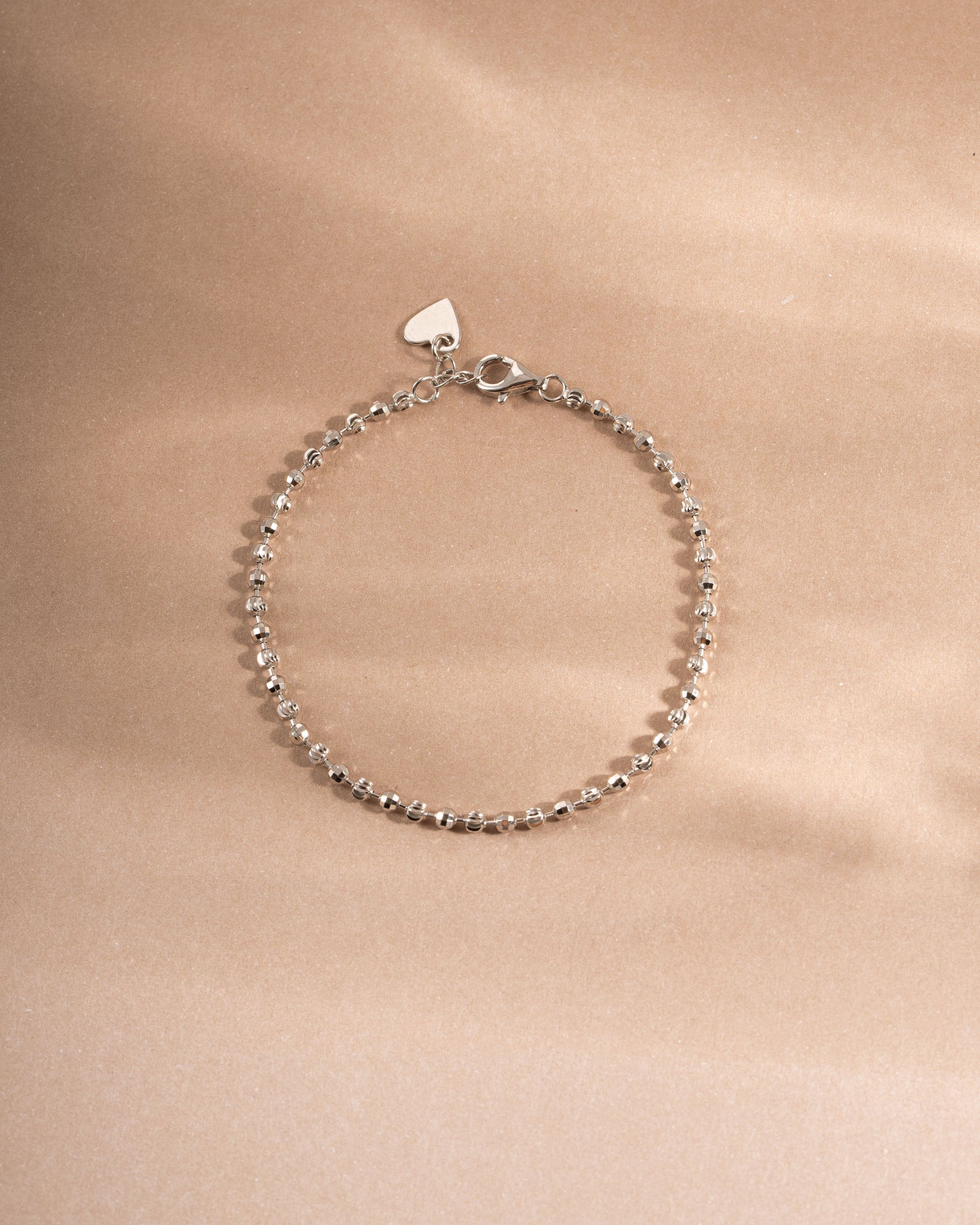 Silver beaded bracelet on beige background