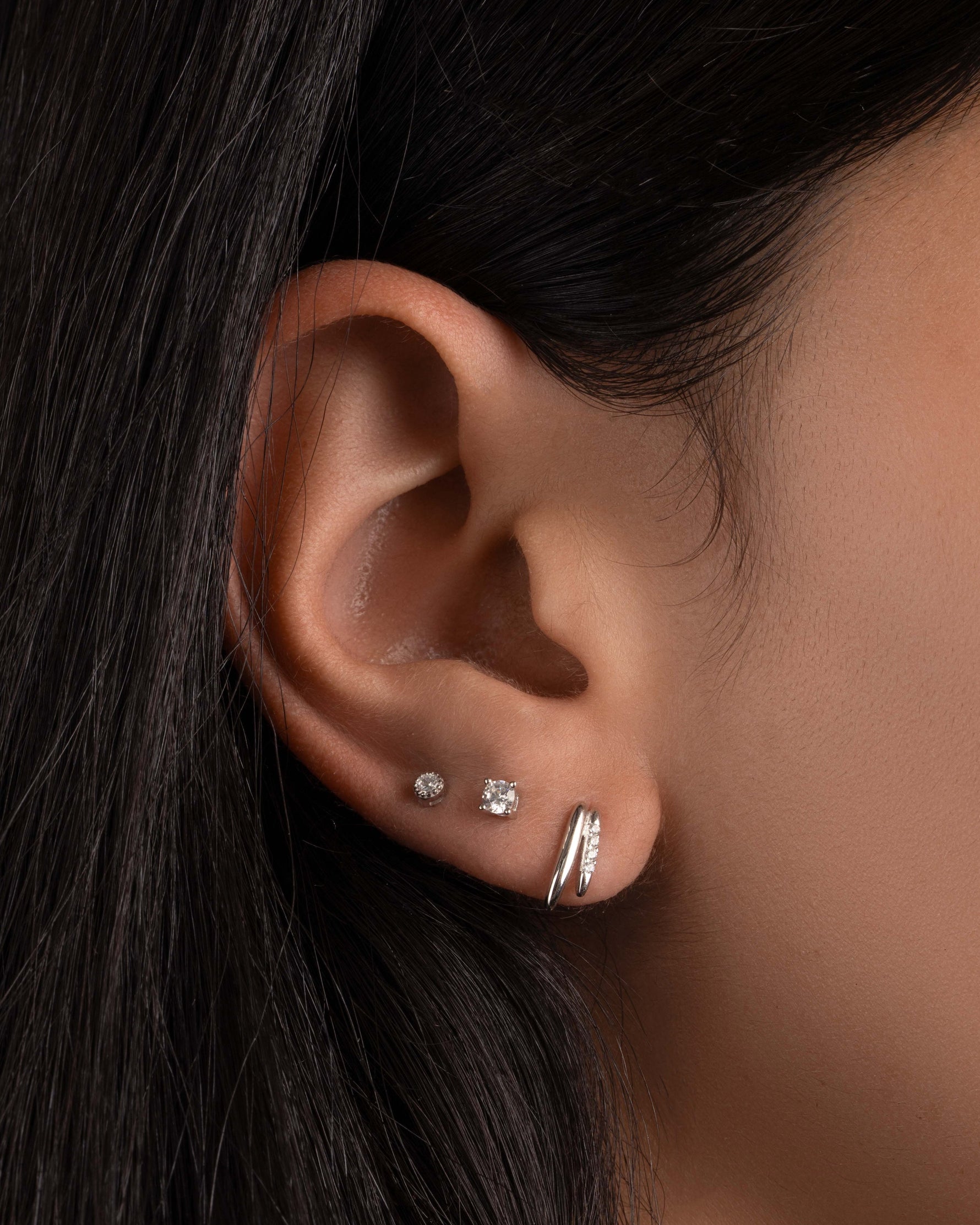 Model wearing small stud earrings featuring silver geometric earrings, and small stud earrings in the second piercing and third piercing