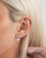 Close up of a model wearing minimalist earrings wearing drop earrings and diamond stud earrings, with a ball stud in her third hole