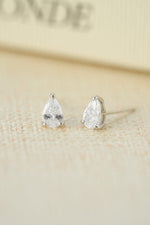 Sterling silver wedding jewelry featuring silver diamond stud earrings on a beige background