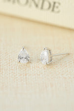 Pair of sterling silver teardrop stud earrings on a beige background