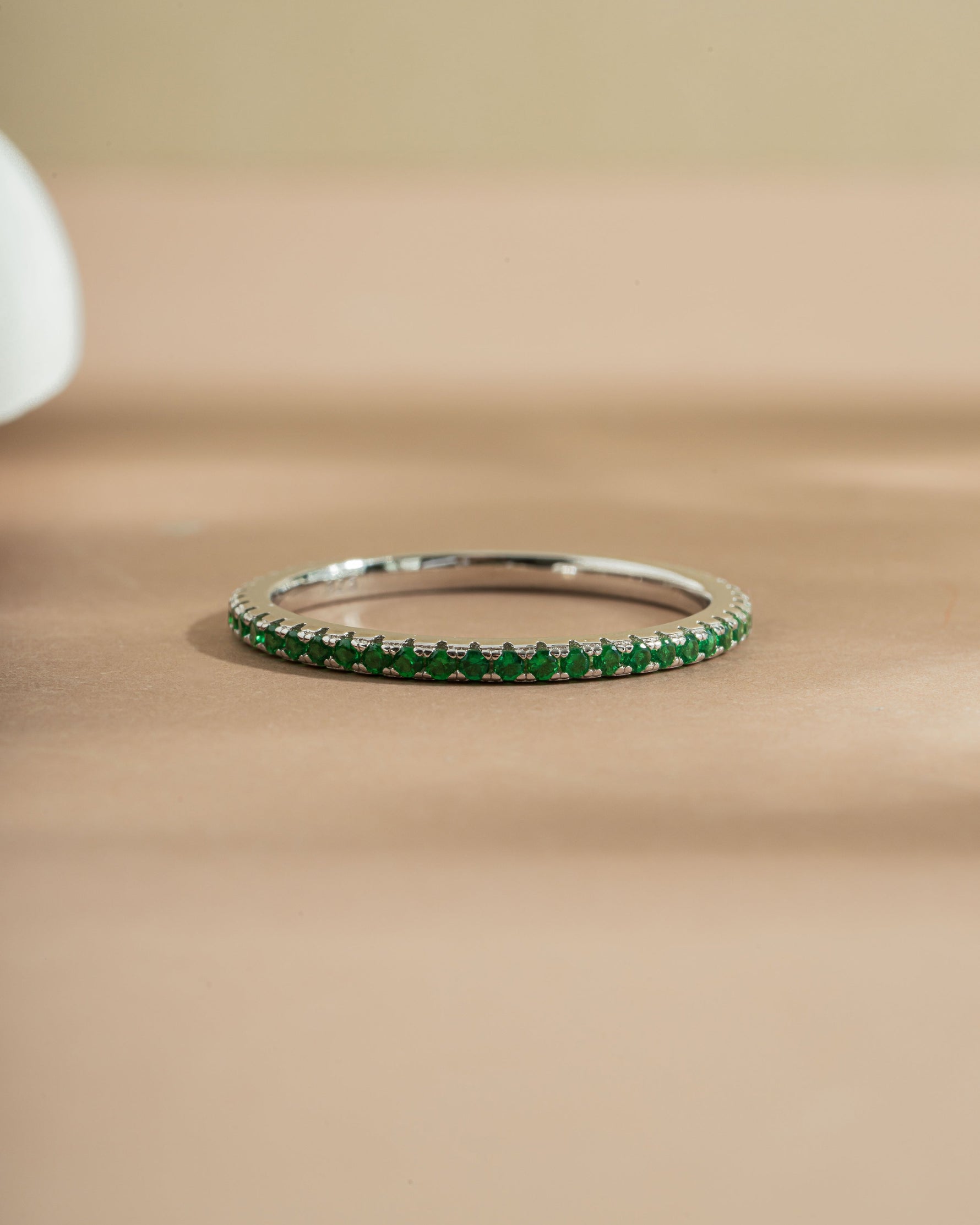 Sterling silver emerald green stacking ring on beige background