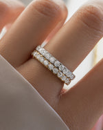 Model wearing two stackable rings, one is a gold diamond promise ring, and one is a 925 sterling silver eternity band 
