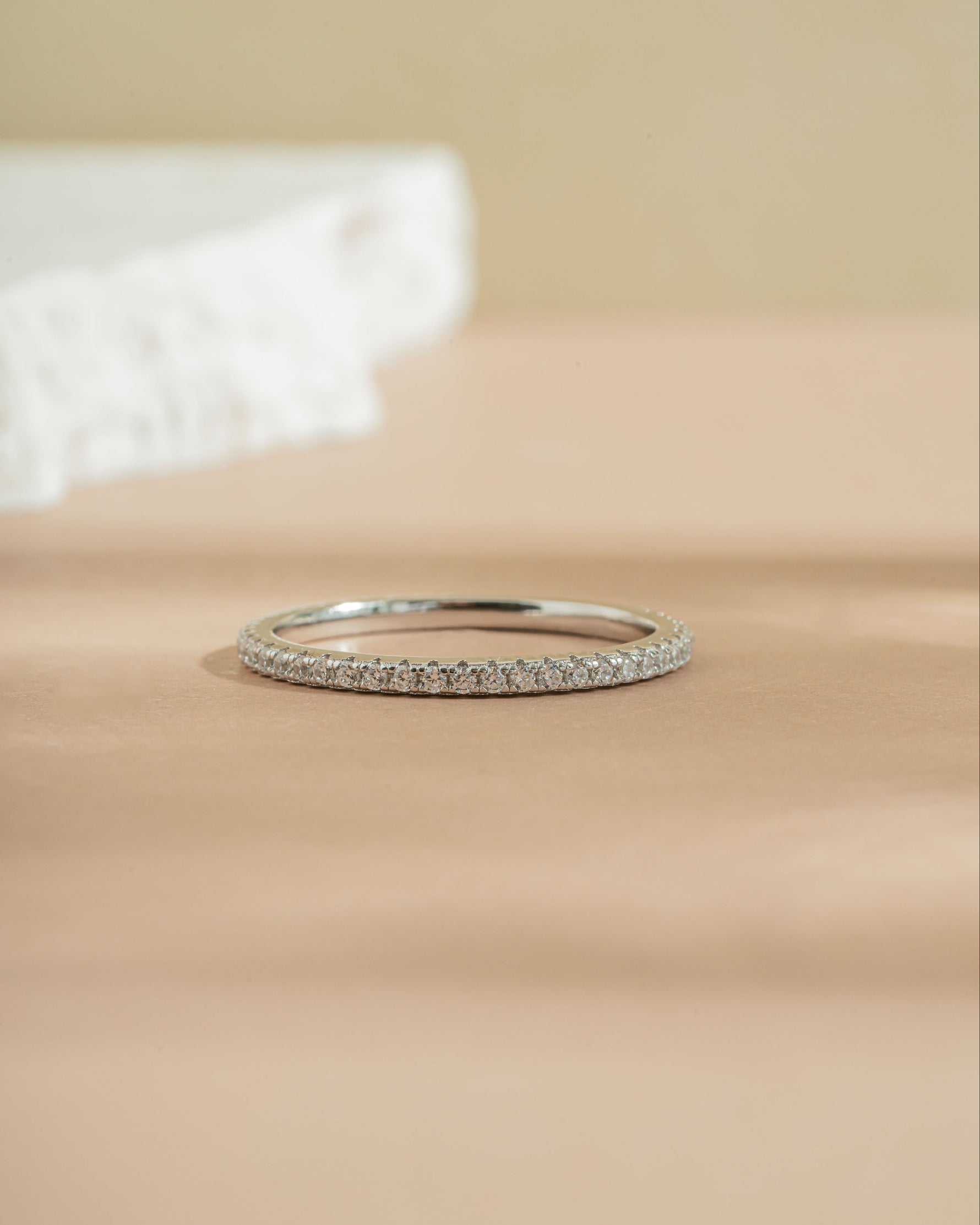 Sterling silver diamond eternity band on beige surface