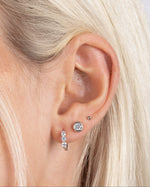 Model wearing silver minimalist earrings featuring sterling silver small stud earrings, cubic zirconia small stud earrings, and silver huggie earrings