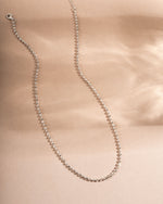 Sterling silver chain stacking necklace on a beige background