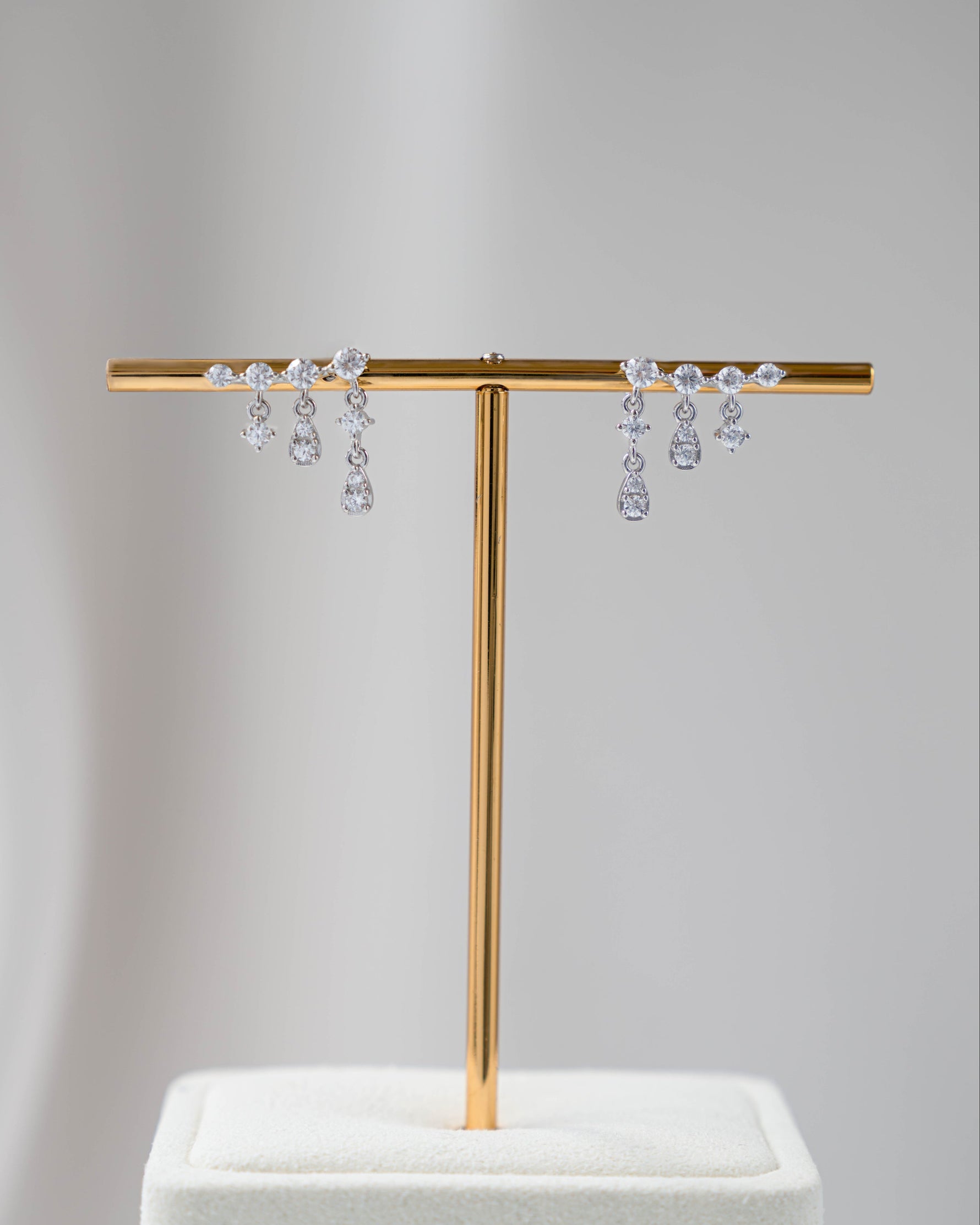 Sterling silver dangling earrings with a tassel earring design on an earring stand