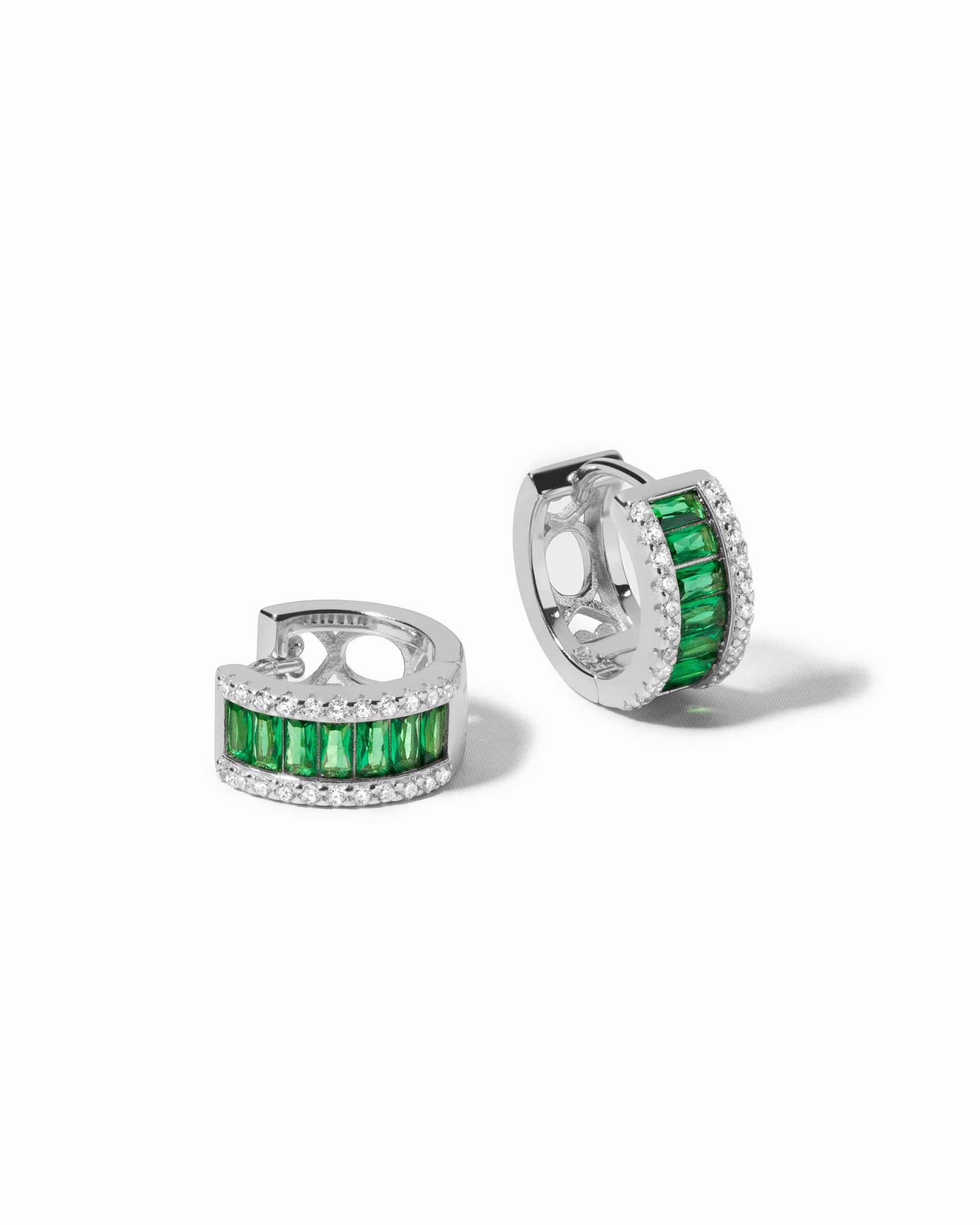 Pair of sterling silver huggie hoop earrings with green gemstones on a white background