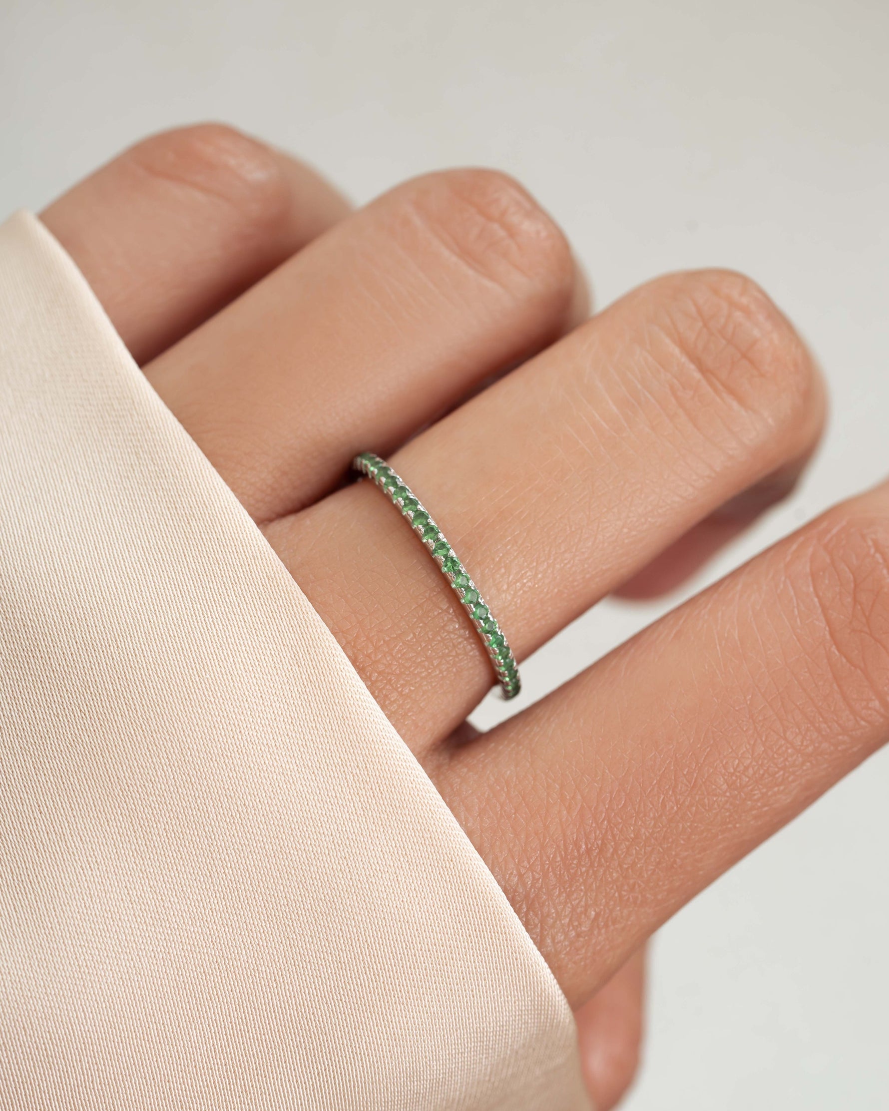 Thin emerald eternity ring on model