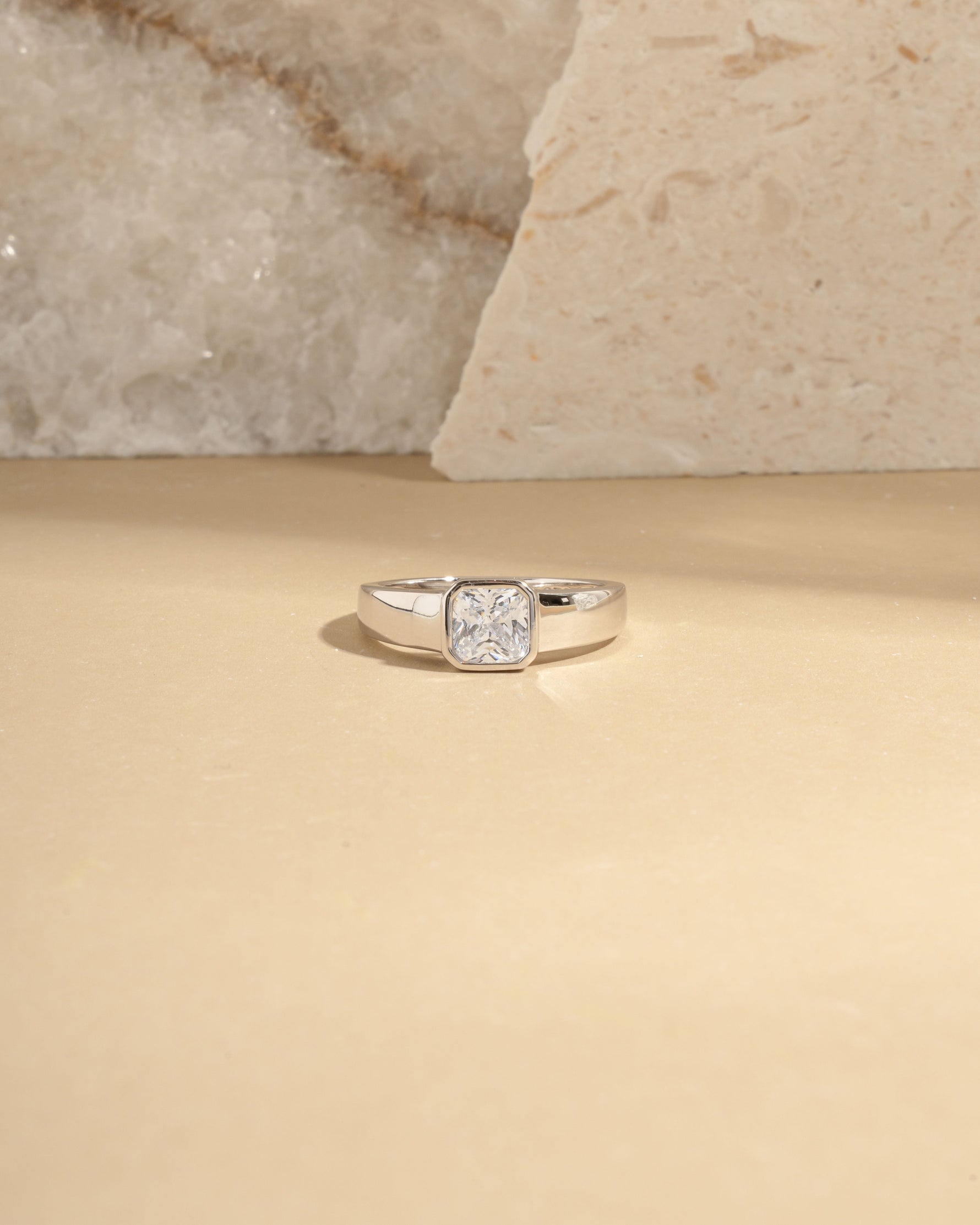 Closeup image of sterling silver bezel set dome ring on beige background