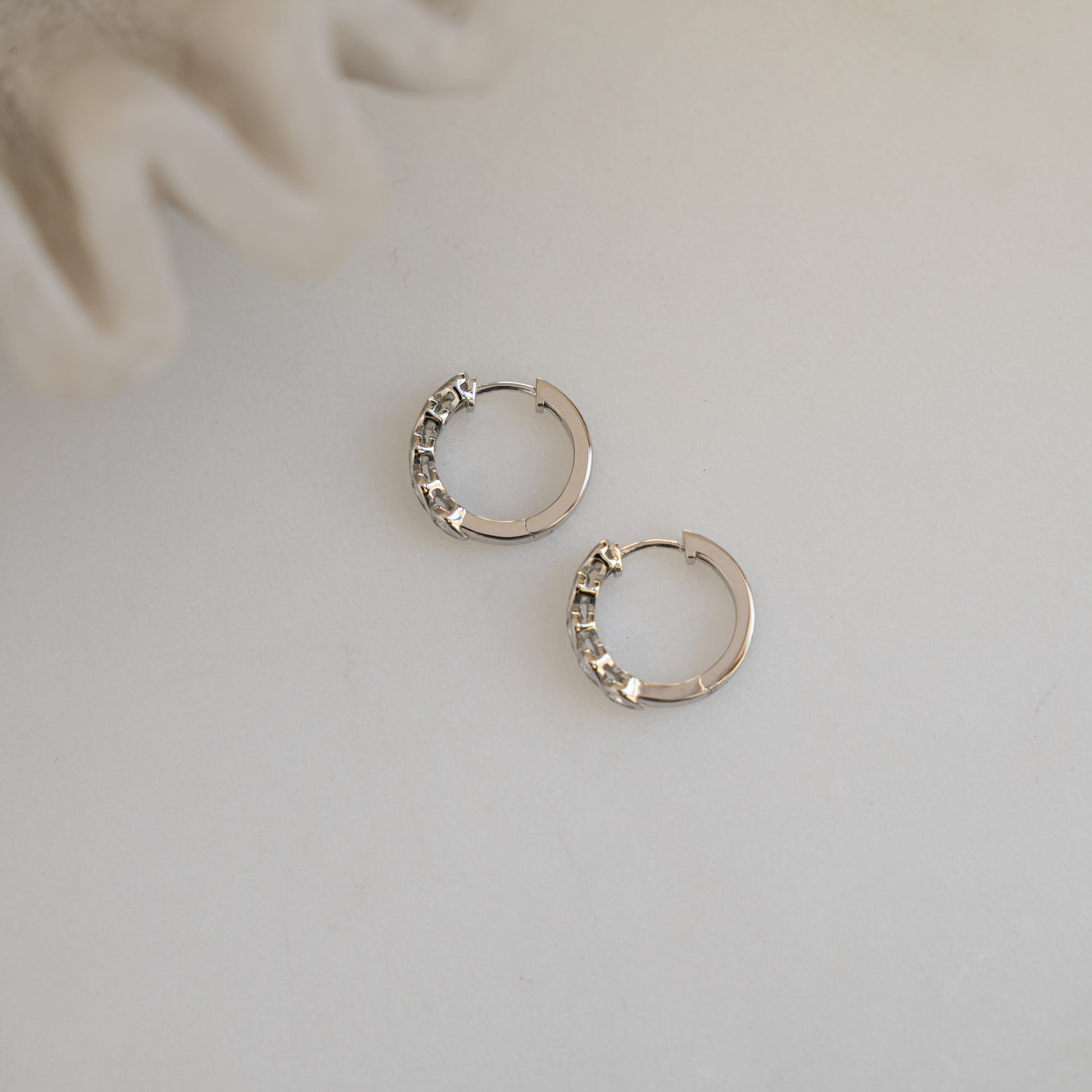 flay lay of huggie earrings in silver, highlighting side details with smooth heart detailing. 