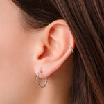 Closeup image of model wearing small sterling silver hoop earrings