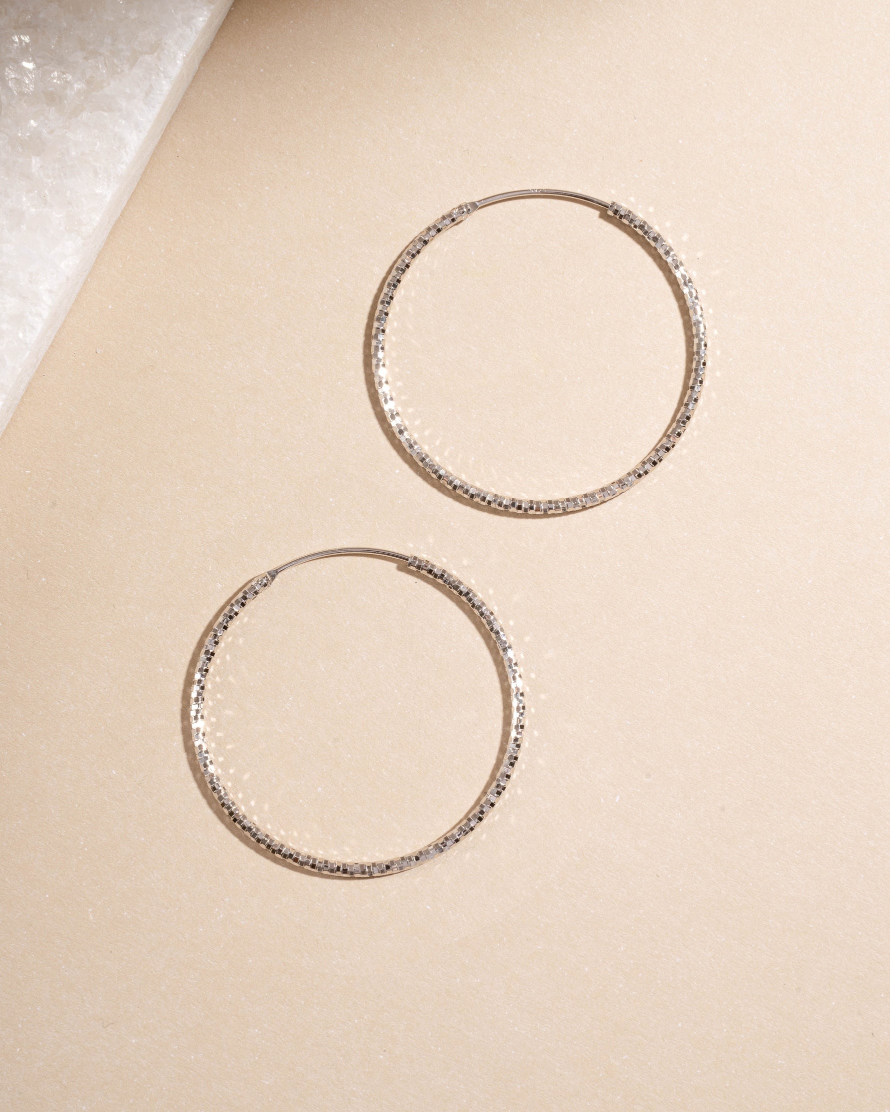 Flatlay of sterling silver 40mm hoop earrings, timeless and lightweight everyday earrings.