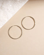 Overhead view of silver 32mm diamond hoops, minimalist earrings and versatile thin hoops for daily wear.