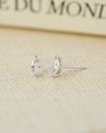 Sterling silver diamond stud earrings on a beige surface