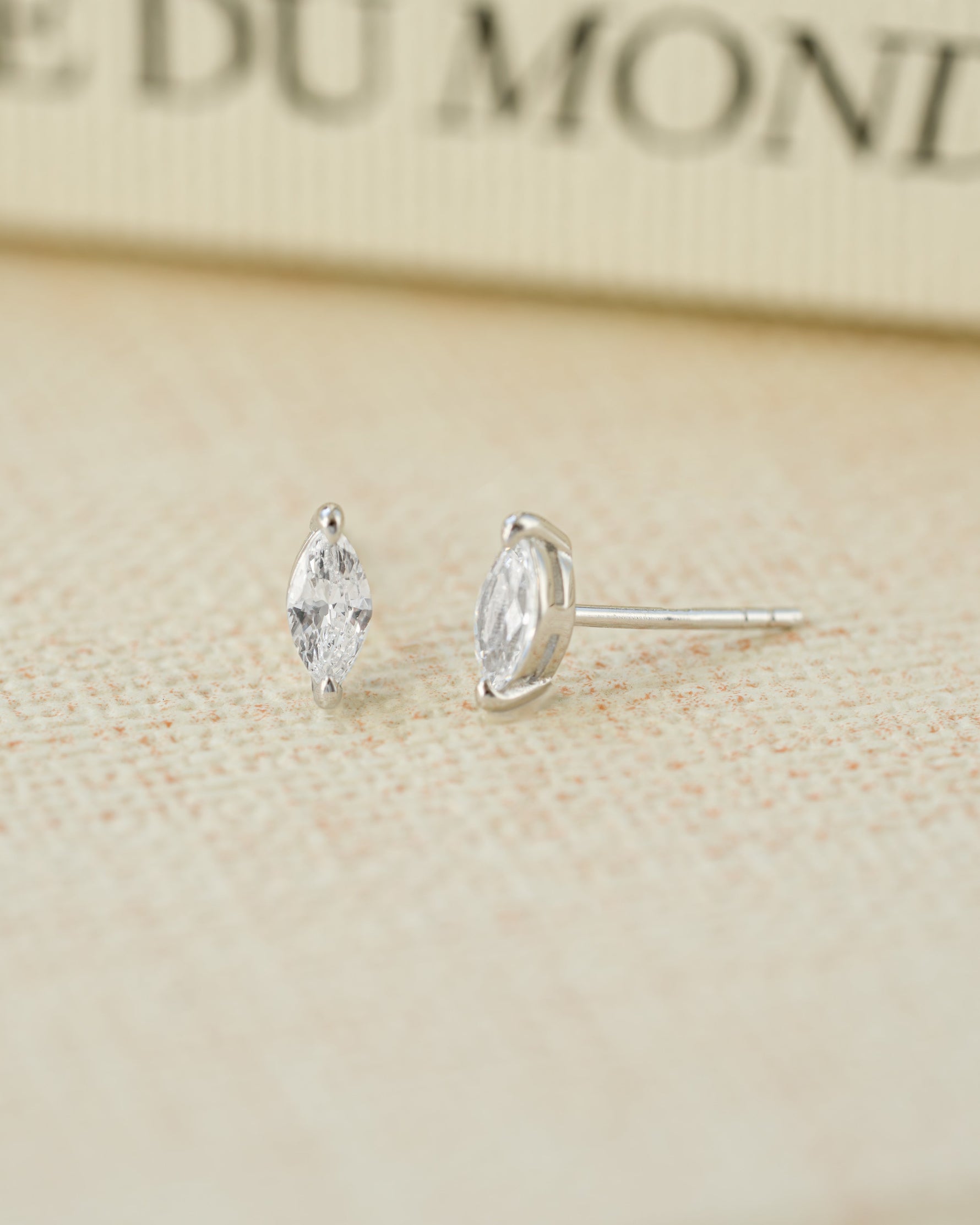 Sterling silver diamond stud earrings on a beige surface