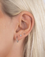 Sterling silver twisted hoop earrings on model with diamond stud earrings and a silver ball stud earring