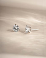 Silver round dainty stud earrings on a neutral background 
