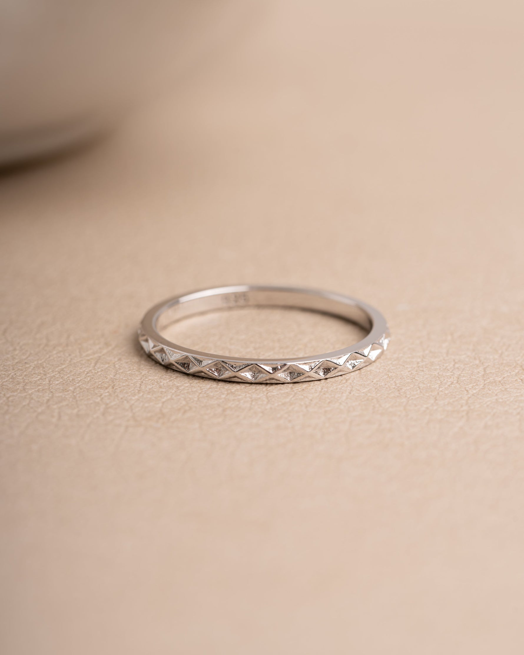 Sterling silver delicate simple ring on a beige background