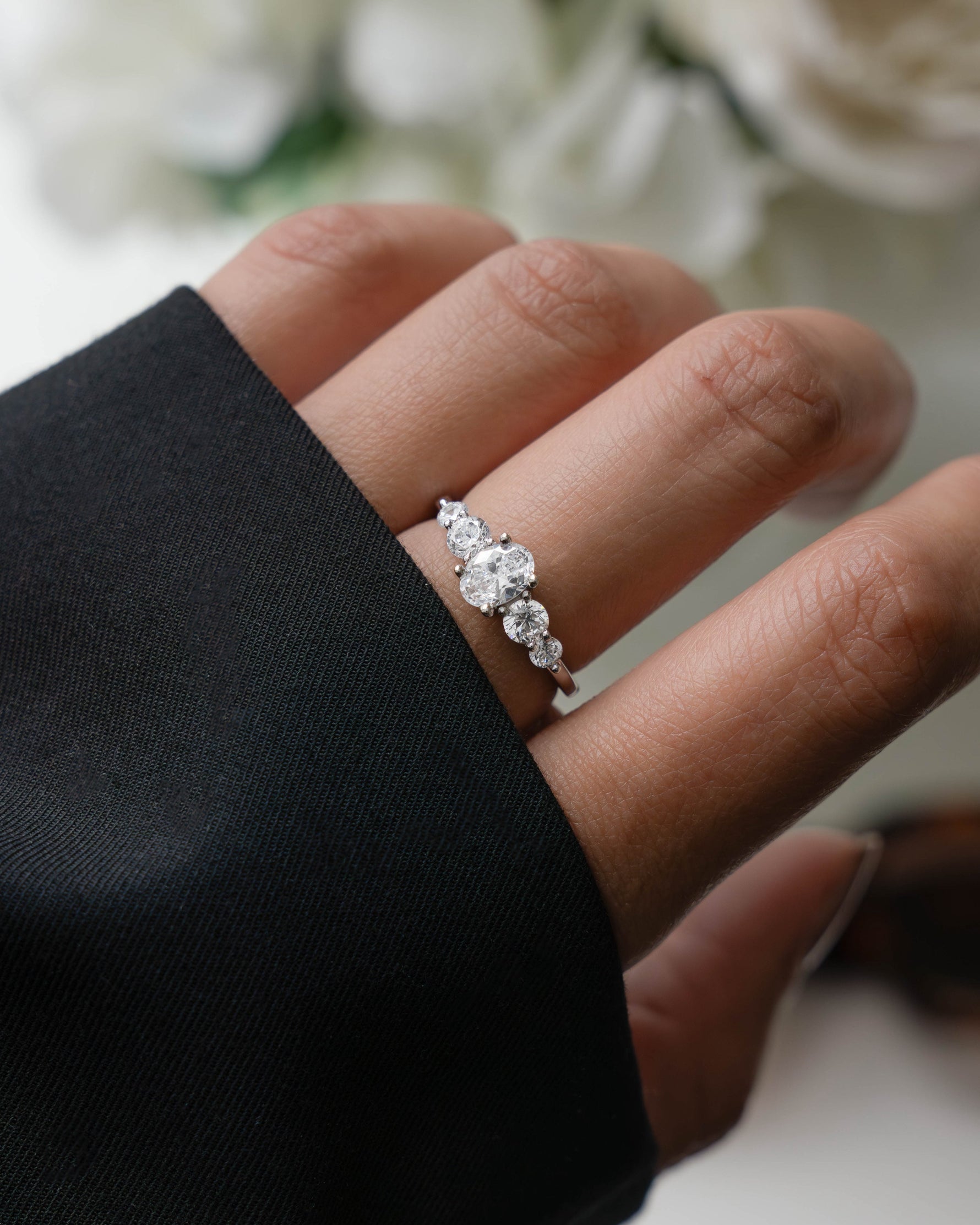 Model wearing silver diamond ring with an oval ring design