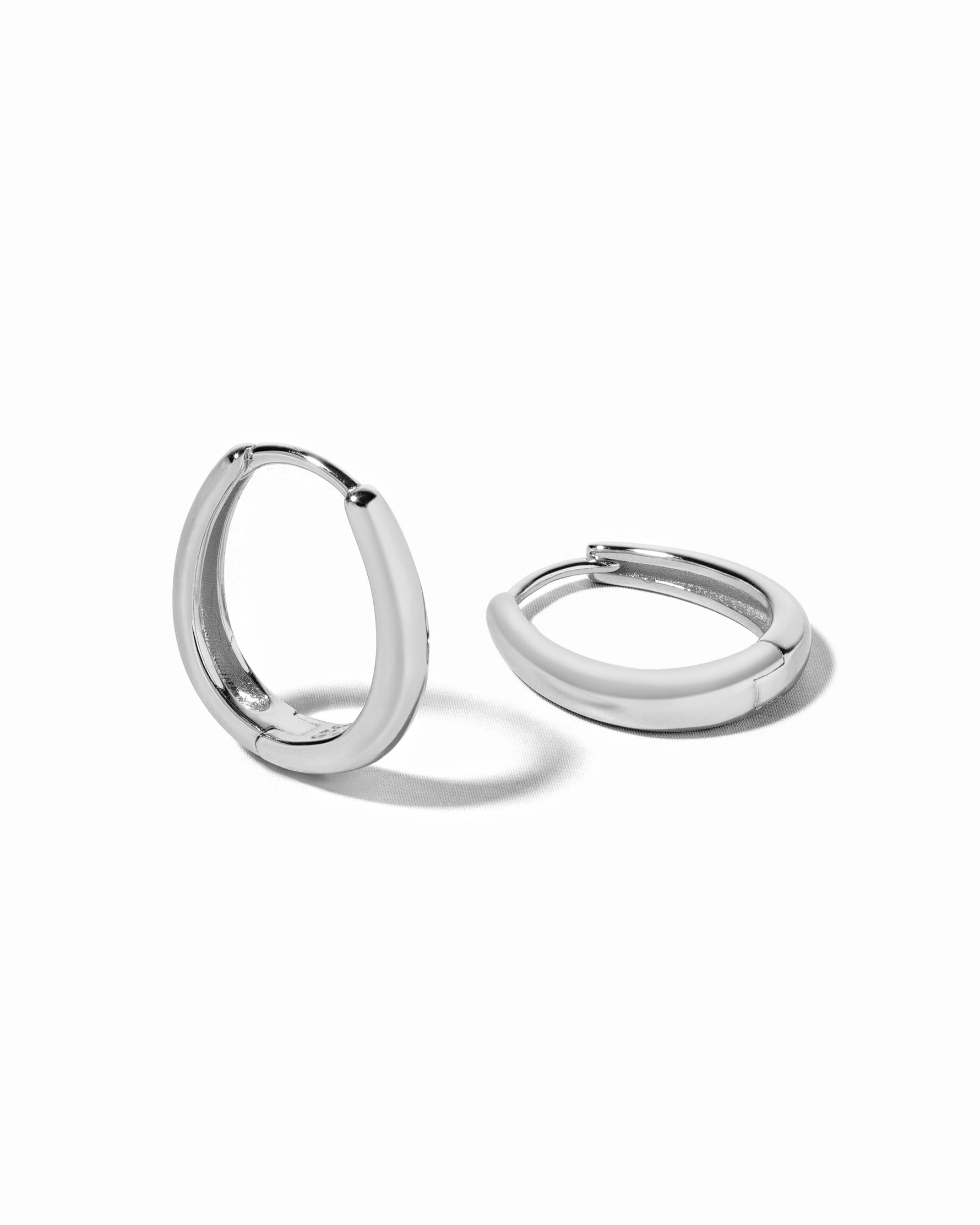 Pair of sterling silver oval hoop earrings on a white background
