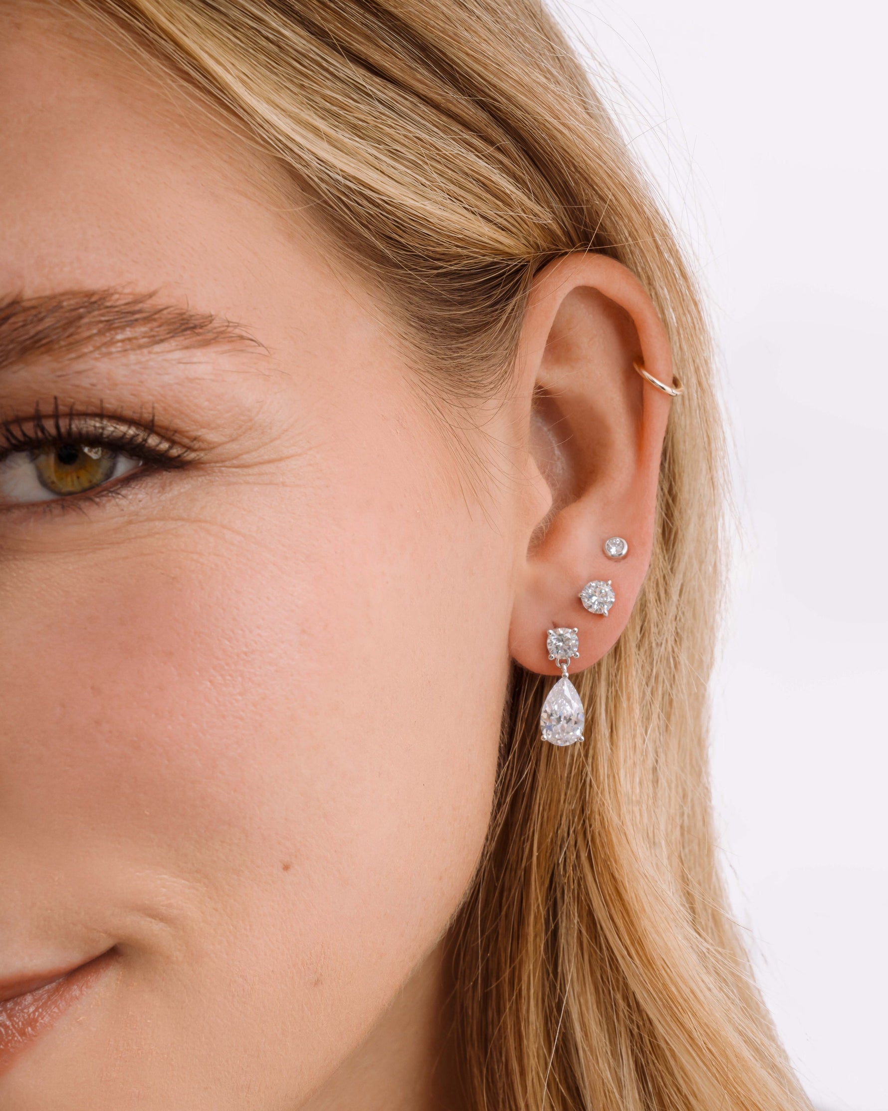 Sterling silver diamond earring stack on model featuring dangle drop earrings, a diamond solitaire stud, and a bezel set stud earring on model