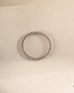 Silver ring with a textured design on a light beige surface