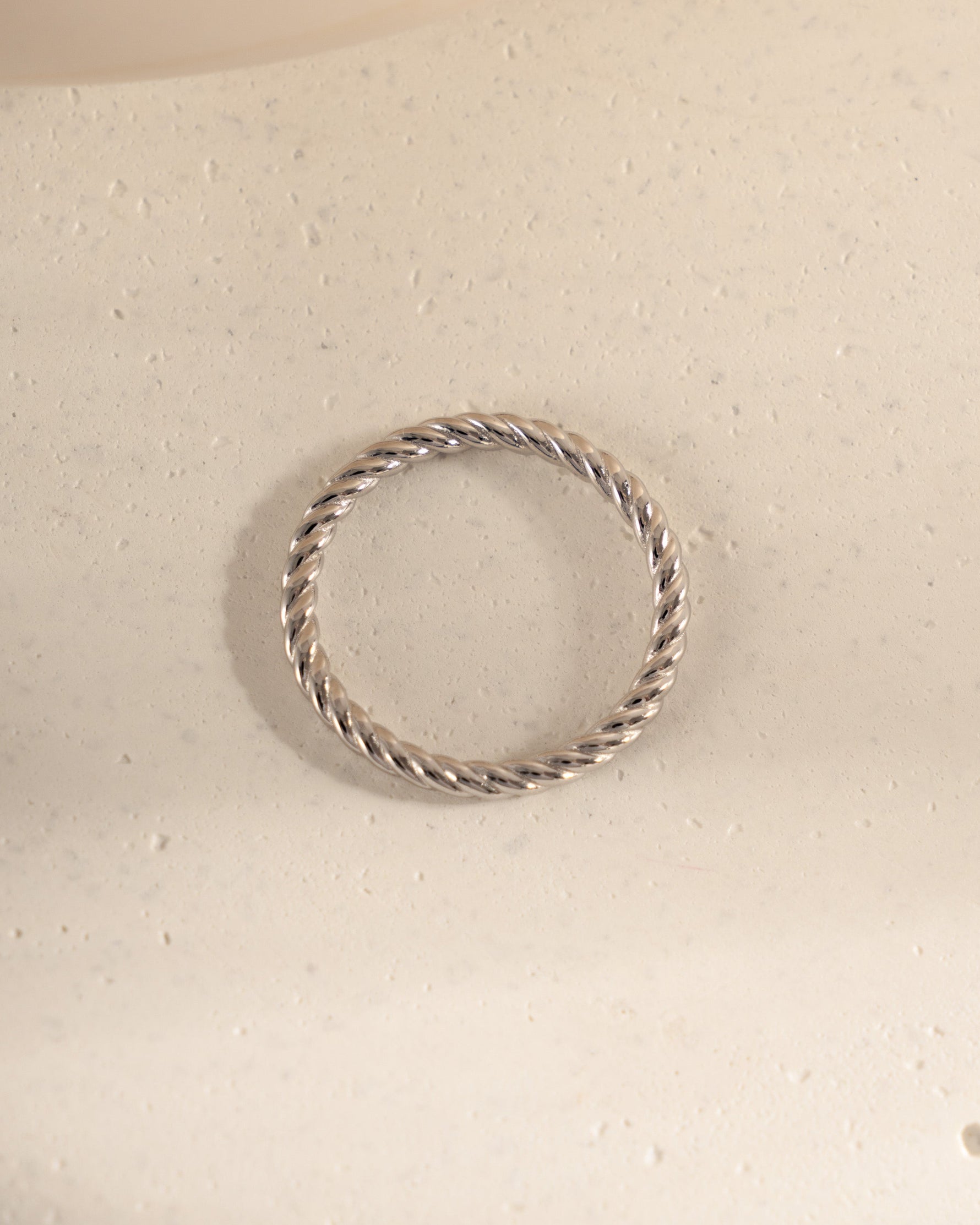 Silver ring with a textured design on a light beige surface