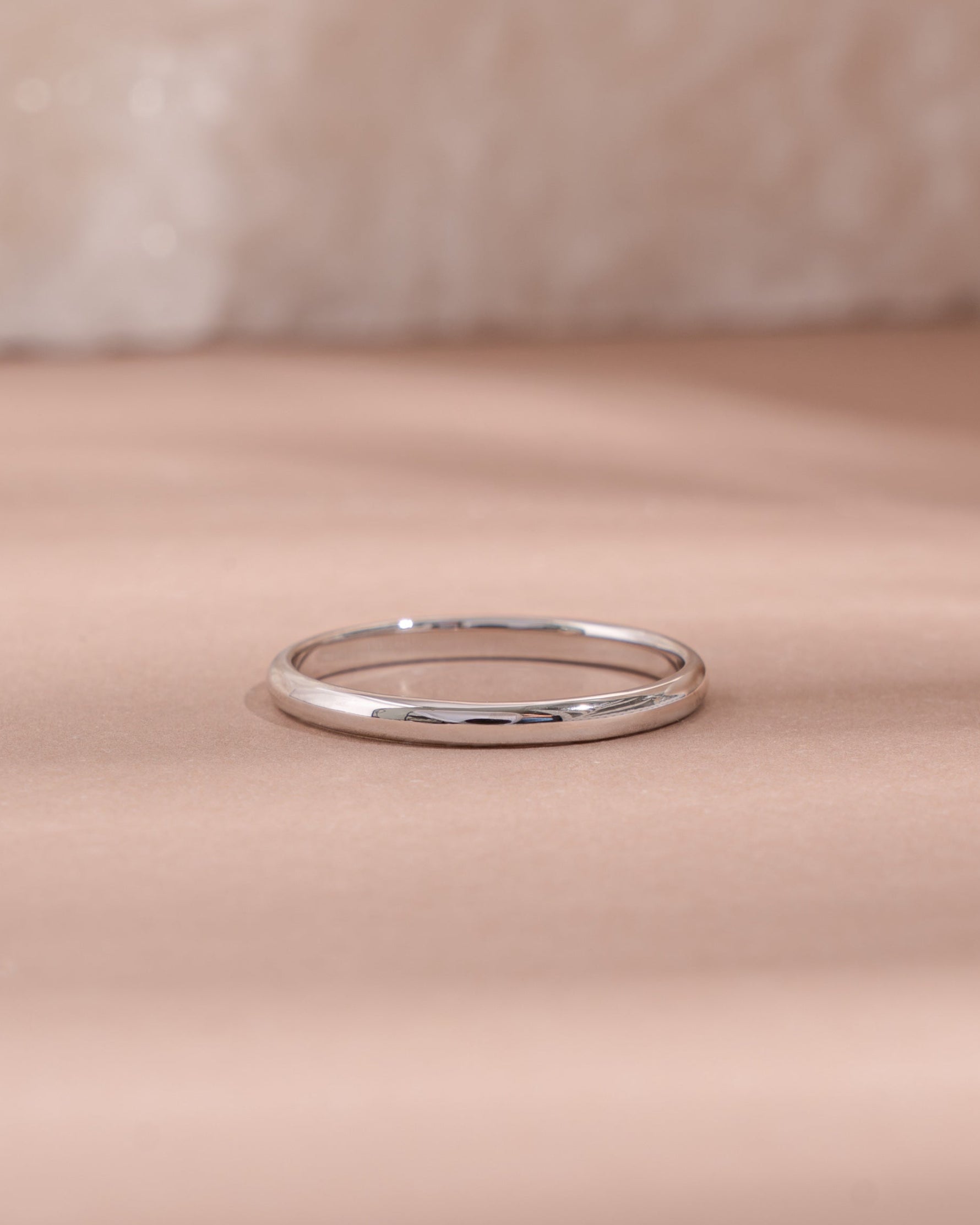 Silver simple ring on a soft pink fabric surface