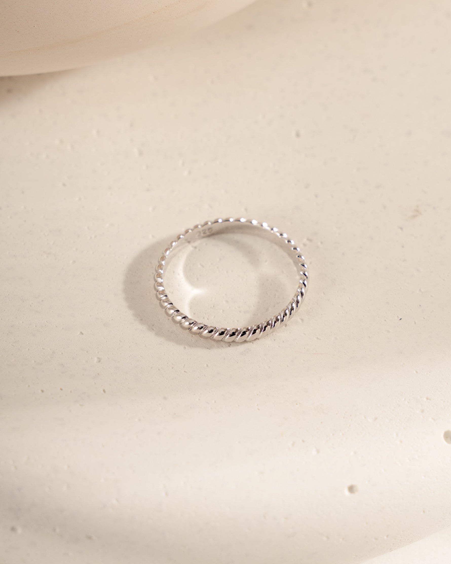 Silver ring on a textured beige surface