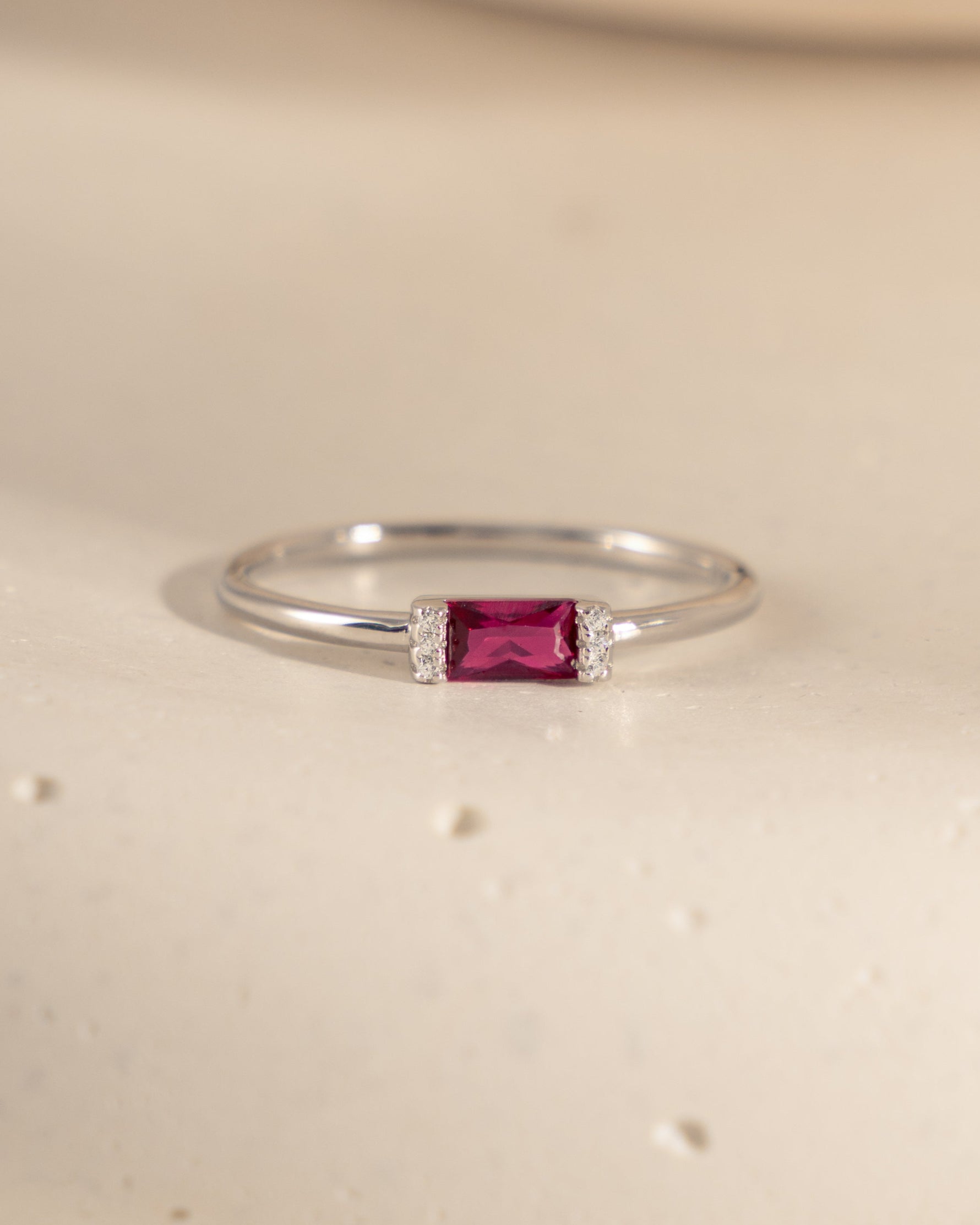 closeup image of birthstone jewelry featuring a ruby baguette ring