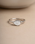 Sterling silver wedding jewelry featuring a silver stackable ring on a beige surface