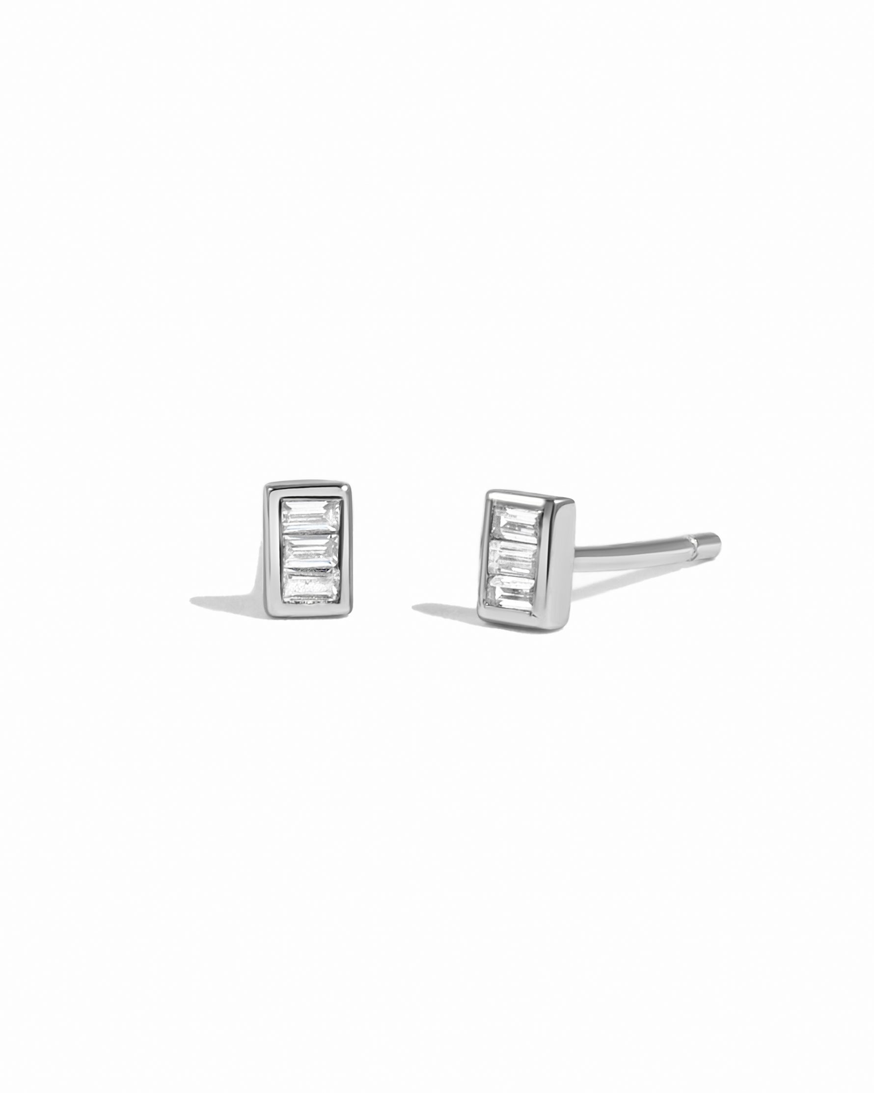 Pair of silver tiny stud earrings with baguette cut stones on a white background
