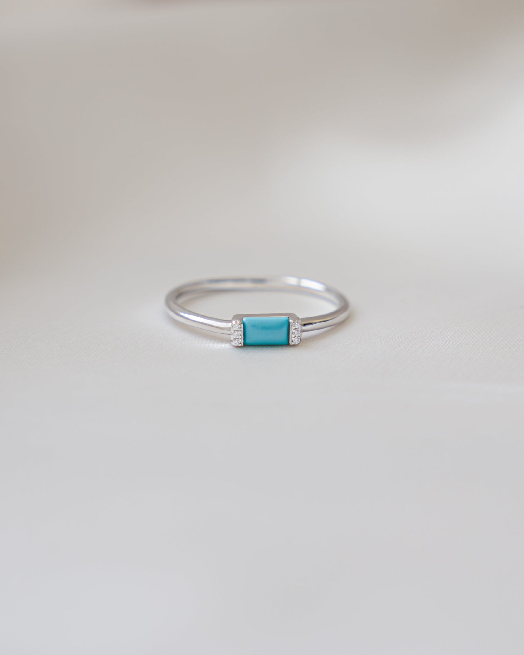 sterling silver baguette gemstone ring with a turquoise stone on a light gray background
