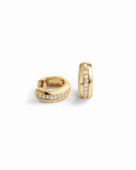 Close-up of dainty diamond huggie earrings in a minimalist style.