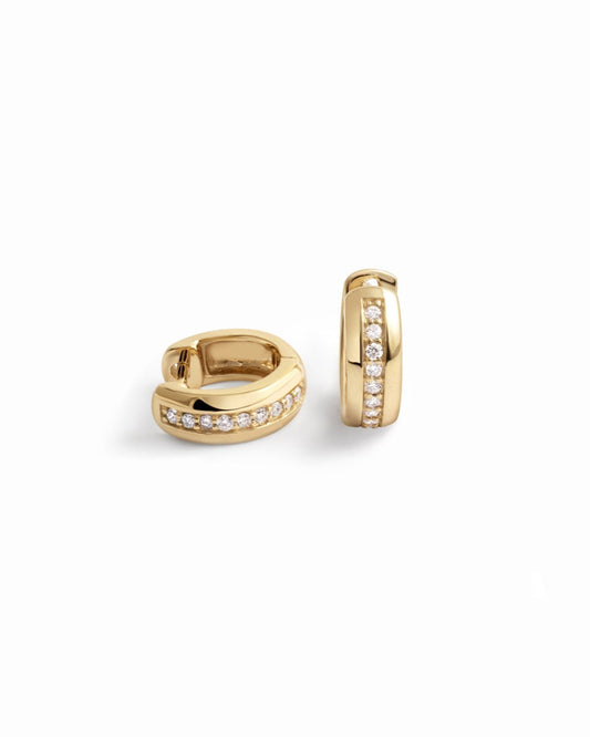 Close-up of dainty diamond huggie earrings in a minimalist style.
