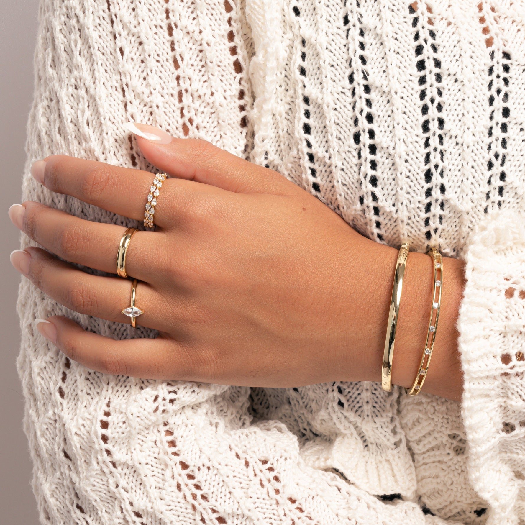 model wearing gold jewelry featuring bangle bracelets, one studded bangle bracelet and one solid bangle 