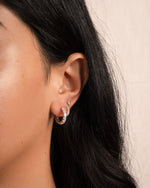 model wearing a silver earring stack featuring cubic zirconia hoop earrings and matching pave huggies, paired with a solitaire stud earring