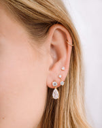 Gold diamond earring stack featuring, elegant earrings with a pear drop design, a charm earring, and a stud earring