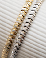 Two stacking tennis bracelets featuring a gold chain bracelet and a silver chain bracelet 