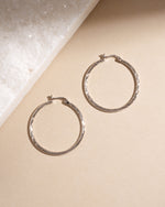 Vintage earrings featuring silver hoop earrings on a beige surface