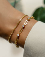 Gold bracelet stack featuring a box chain bracelet and a diamond chain link bracelet on model
