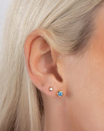 Model wearing aquamarine jewelry featuring aquamarine earrings, and dainty stud earrings
