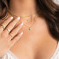 gold necklace stack on model featuring small cross pendant necklace, tiny bezel necklace, and thin rope chain necklace