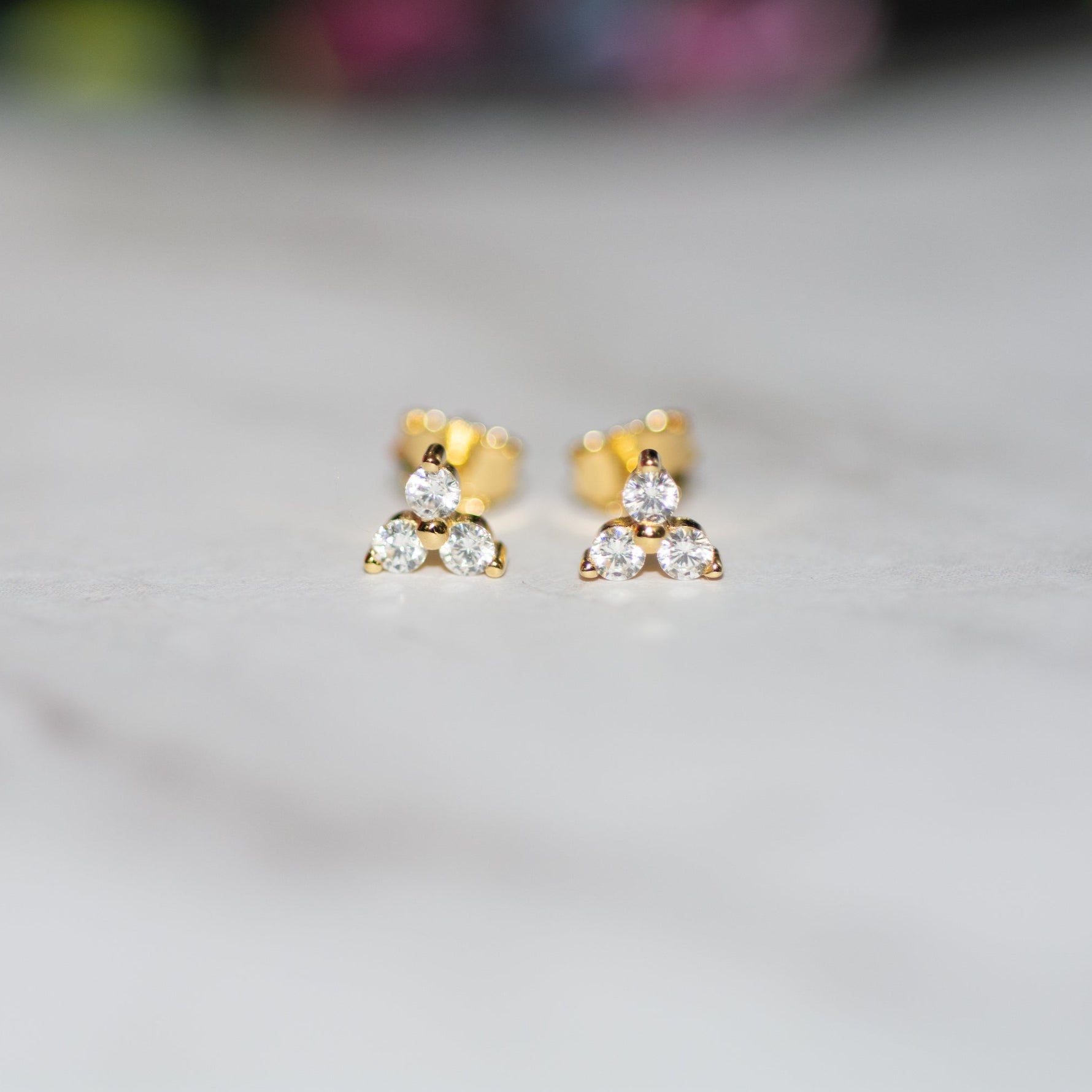 closeup image of gold three stone cluster stud earrings