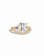 Toi Et moi matching band set, featuring, a pear-cut and emerald cut stone on a gold band, with a matching pave curved gold band on a white background